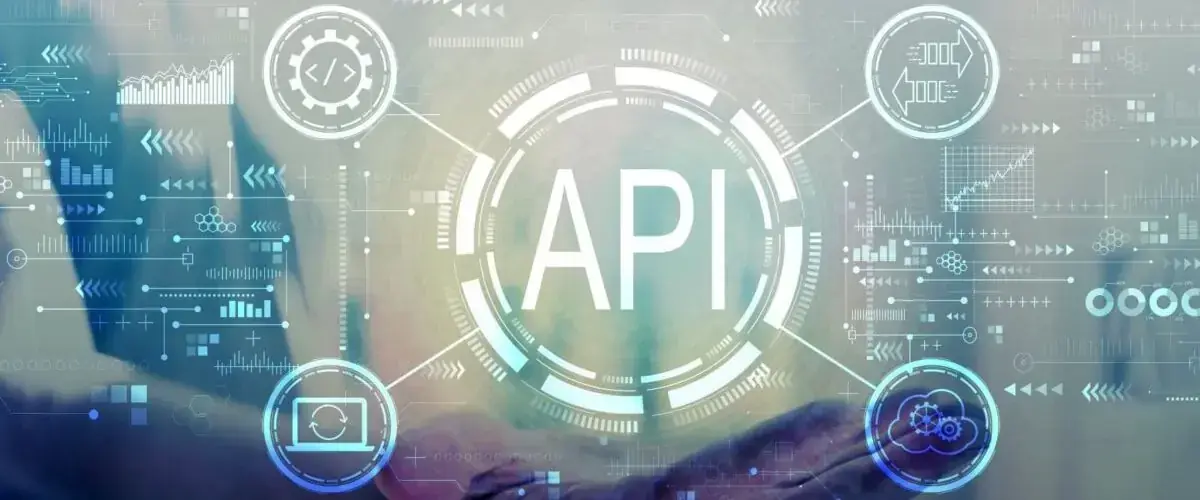 La scritta API al centro di un'interfaccia tecnologica, con un portatile sullo sfondo