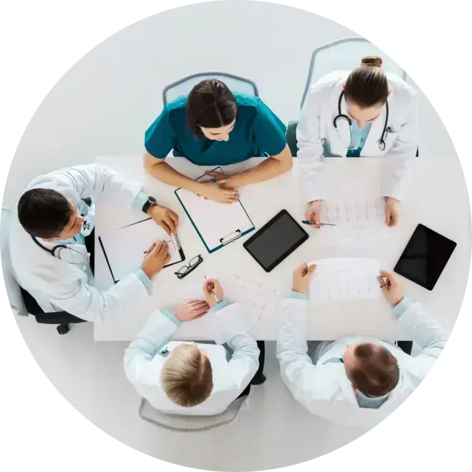 Veduta dall'alto di un tavolo con professionisti sanitari al lavoro fra tablet e documenti